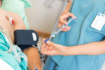 Image showing Nurse Injecting Dosage In IV Tube Attached To Patient