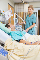Image showing Nurse Examining Young Patient Lying On Bed