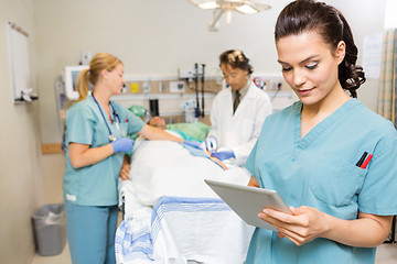 Image showing Nurse Using Digital Tablet While Doctor And Colleague Operating