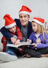 Image showing Father With Children Reading Book During Christmas