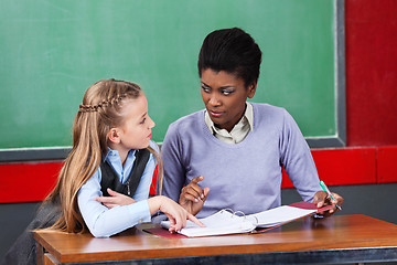 Image showing Female Teacher Looking At Schoolgirl In Classroom