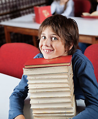 Image showing Schoolboy Resting Chin On Stacked Books At Table