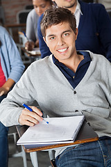 Image showing Man With Exam Paper Sitting At Desk In Classroom