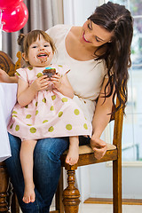 Image showing Birthday Girl Eating Cupcake While Sitting On Mother's Lap