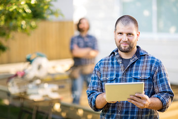 Image showing Manual Worker Holding Digital Tablet With Coworker Standing In B