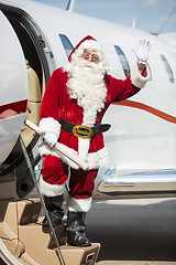 Image showing Santa Waving Hand While Standing On Private Jet's Ladder