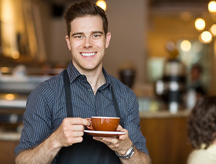 Image showing Happy Waiter Holding Coffee Cup In Cafeteria