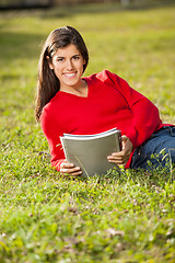 Image showing Student Holding Books While Relaxing On Grass At Campus