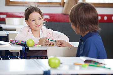 Image showing Little Girl Giving Pencil To Boy In Classroom