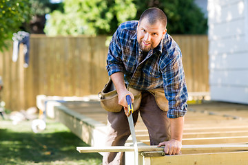 Image showing Manual Worker Sawing Wood At Construction Site