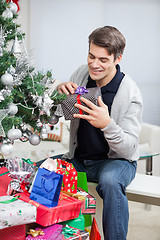 Image showing Man Holding Present While Sitting By Christmas Tree