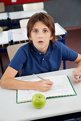 Image showing Shocked Schoolboy With Cheat Sheet Sitting At Desk