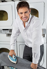 Image showing Businessman Ironing Jeans In Laundry