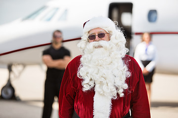 Image showing Man In Santa Costume Standing Against Private Jet