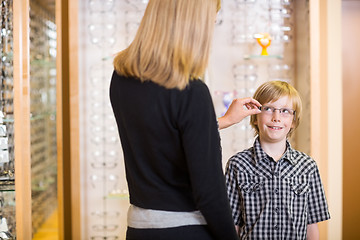 Image showing Mother Trying Spectacles On Son At Shop