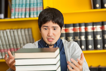 Image showing Student Looking At Pile Of Books In University Library