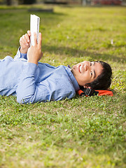 Image showing Relaxed Man Holding Book While Lying On Grass At Campus