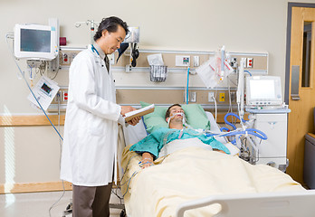 Image showing Doctor With Clipboard Examining Patient's Report