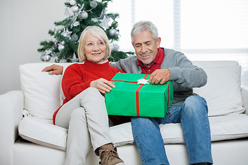 Image showing Couple With Christmas Gift Sitting On Sofa