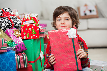 Image showing Boy Sitting By Stacked Christmas Presents