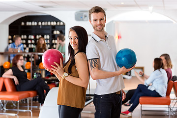 Image showing Friends Standing Together With Bowling Balls in Club