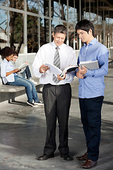 Image showing Teacher And Student Discussing Over Book On University Campus