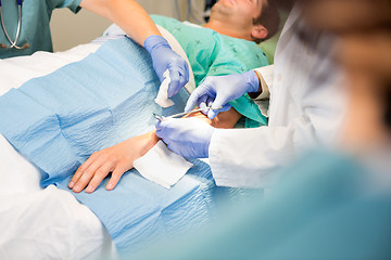 Image showing Doctor Stitching Patient's Wound While Nurse Assisting Him