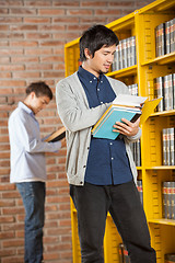 Image showing Student Reading Book While Friend Standing In Background