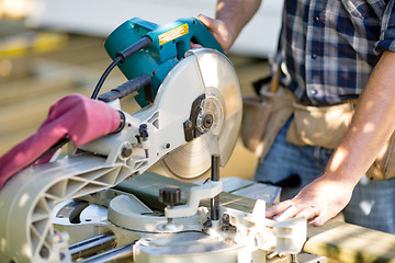 Image showing Carpenter Cutting Wooden Plank With Table Saw At Site