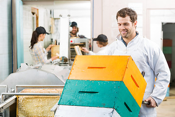 Image showing Male Beekeeper Holding Trolley Of Stacked Honeycomb Crates