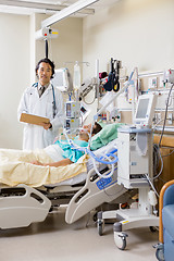 Image showing Doctor With Patient's Report Standing By Bed