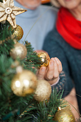 Image showing Couple Selecting Baubles Hanging On Christmas Tree At Store
