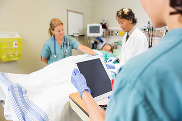 Image showing Nurse Holding Digital Tablet While Doctor And Colleague Treating