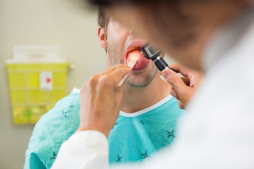 Image showing Doctor With Depressor And Otoscope Examining Patient's Tongue