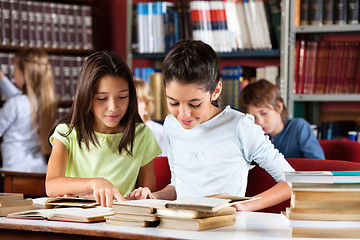 Image showing Schoolgirls Reading Book Together At Table In Library