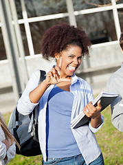 Image showing Student Holding Books While Gesturing Loser Sign On Campus