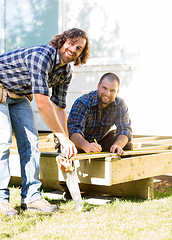 Image showing Workers Measuring Wood Together At Construction Site