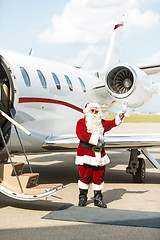 Image showing Santa Using Waving Against Private Jet