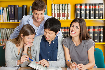 Image showing Female Student With Friends Reading Book In Library