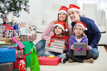 Image showing Family In Santa Hats Sitting By Christmas Presents