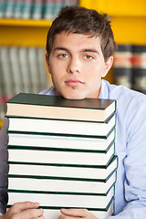 Image showing Student Resting Chin On Stacked Books In Library