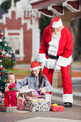 Image showing Santa Claus Looking At Children Opening Christmas Presents