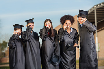 Image showing Graduate Students Looking Through Diplomas On Campus