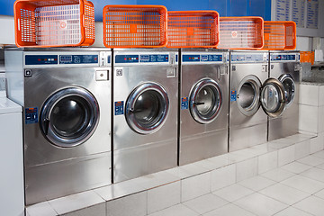 Image showing Washing Machines And Empty Baskets In A Row