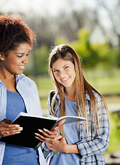 Image showing Beautiful Woman With Friend Holding Book In Campus