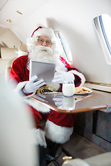 Image showing Santa Holding Digital Tablet In Private Jet