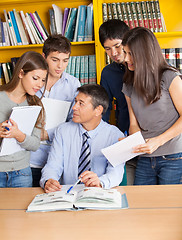 Image showing Teacher With Books Explaining Students In College Library