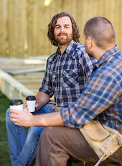 Image showing Worker Holding Disposable Cup While Sitting With Coworker