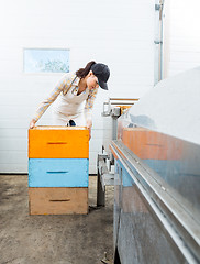 Image showing Beekeeper With Stacked Honeycomb Crates In Factory