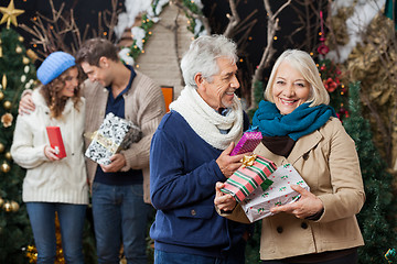 Image showing Senior Couple Holding Christmas Presents With Children In Backgr